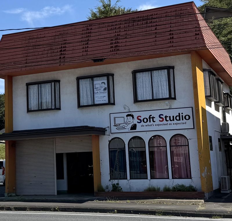 ソフトスタジオ 千厩ベースの外観。白い壁に赤い屋根の2階建ての建物で、道路に面した壁に「Soft Studio」の看板が掲げられている。